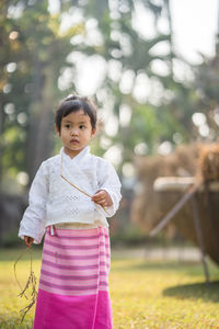 Girl holding stick while standing on grass at park