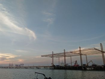 Suspension bridge over river against cloudy sky