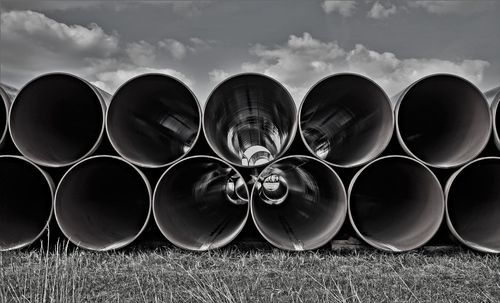 Stack of pipes on field against sky