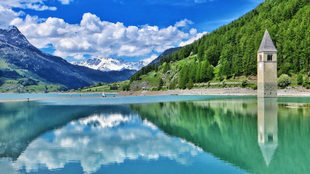 mountain, water, sky, tranquil scene, tranquility, scenics, lake, reflection, beauty in nature, mountain range, nature, built structure, architecture, river, idyllic, day, tree, non-urban scene, panoramic, waterfront