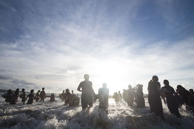 People enjoying in sea against sky during sunny day