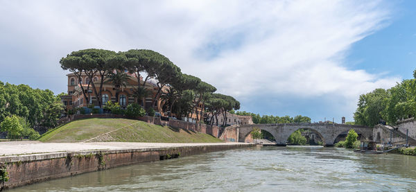 Arch bridge over river against cloudy sky