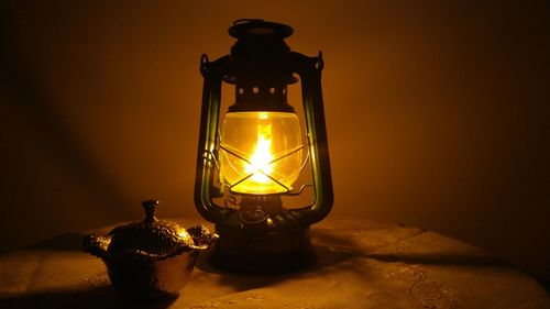 Close-up of illuminated lamp against wall