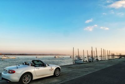 Boats moored on sea against sky at sunset