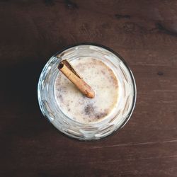 Directly above shot of coquito with cinnamon in glass on wooden table