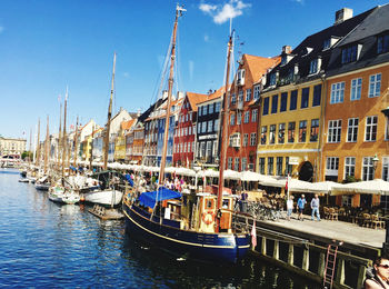 Sailboats moored on canal by buildings in city