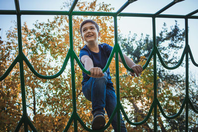 Low angle view of boy playing on outdoor play equipment