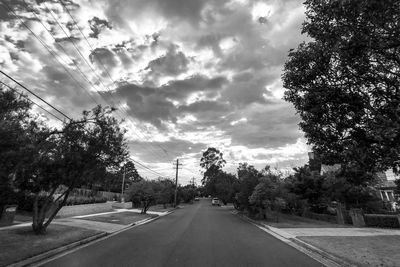 Road amidst trees against sky in city