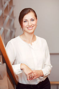 Portrait of beautiful woman standing by railing