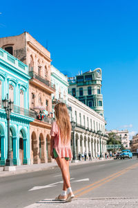 Full length of woman walking on road against clear blue sky