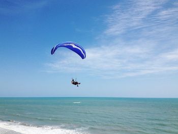 Paragliding over sea against sky