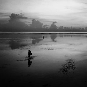 Reflection of silhouette man in water against sky