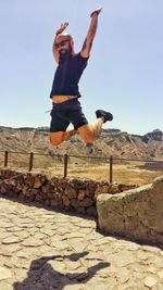 Young woman jumping against clear sky