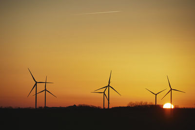 Low angle view of electricity pylon against sky during sunset