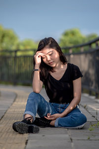 Portrait of young man looking away while sitting outdoors