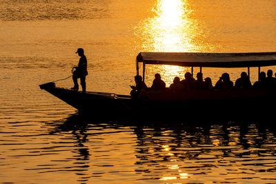 Silhouette people on boat in canal during sunset