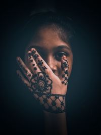 Close-up portrait of a young woman over black background