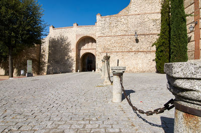 Footpath by old building against clear sky