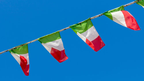 Low angle view of flags flag against clear blue sky