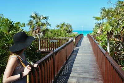 Woman by palm trees on beach against clear sky