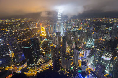 Petronas towers amidst illuminated cityscape against sky at night