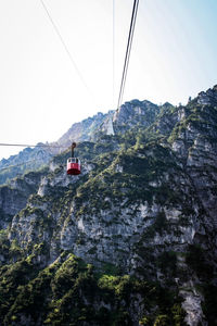 Low angle view of overhead cable car over mountains against sky