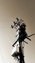 Low angle view of silhouette telephone pole against sky