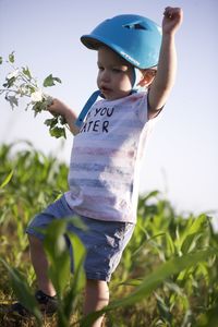 Rear view of boy standing amidst plants