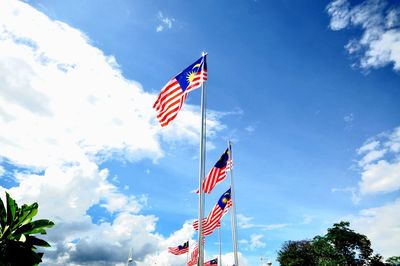 Low angle view of malaysian flags against sky