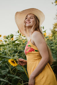 Young woman wearing hat standing against plants