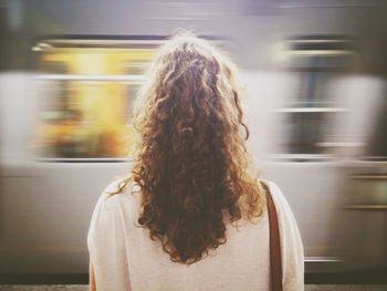 Rear view of young woman in front of train at station