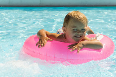 A small child swims in a pink swimming circle in the pool close up