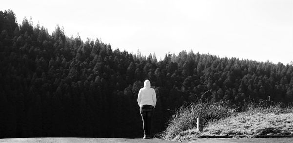Rear view of man standing by tree against sky