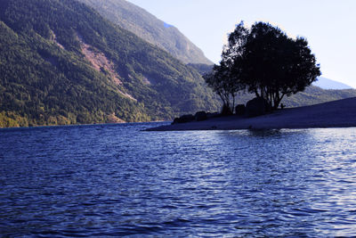 Scenic view of sea by mountain against sky