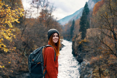 Portrait of smiling young woman standing against trees