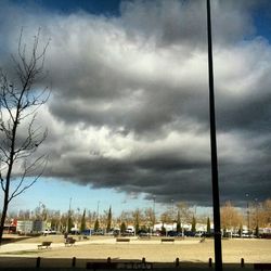 Road passing through city against cloudy sky