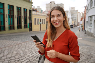 Brazilian business woman holding mobile phone looks at camera in curitiba, brazil