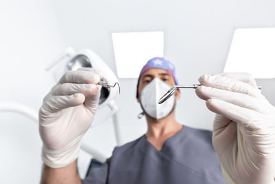 Selective focus on the tools that are using a male dentist with uniform and mask in a dental clinic