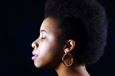 Profile view of young woman with curly hair against black background