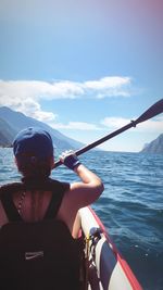 Man riding boat in sea against sky