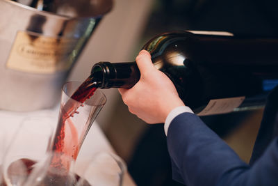 Cropped hand of person pouring wine in glass