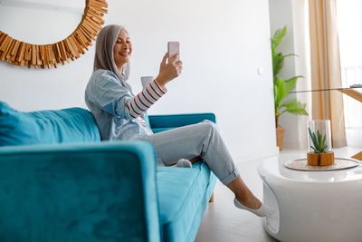 Young woman using mobile phone while sitting at home