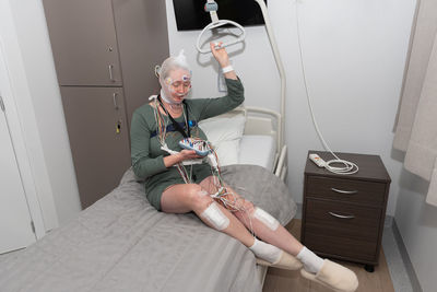 Middle aged woman measuring brain waves, examining polysomnography in sleep lab