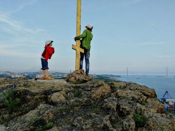 People standing on rock against sky