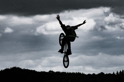 Man performing bicycle stunt against sky