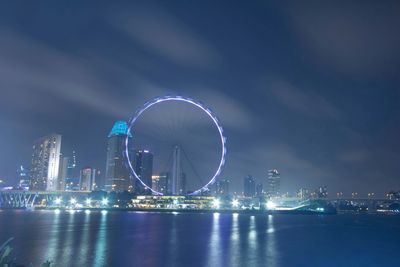 Illuminated ferris wheel in city at night