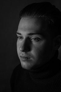 Close-up portrait of young man against black background