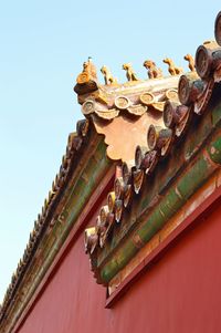 Low angle view of sculptures on roof of building against clear sky