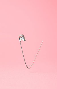 Close-up of safety pin over pink background