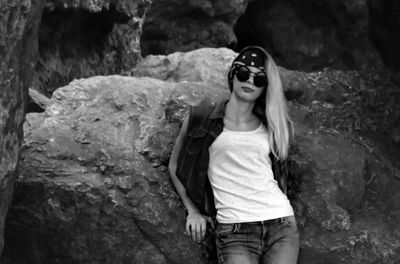 Young woman wearing sunglasses standing on rock